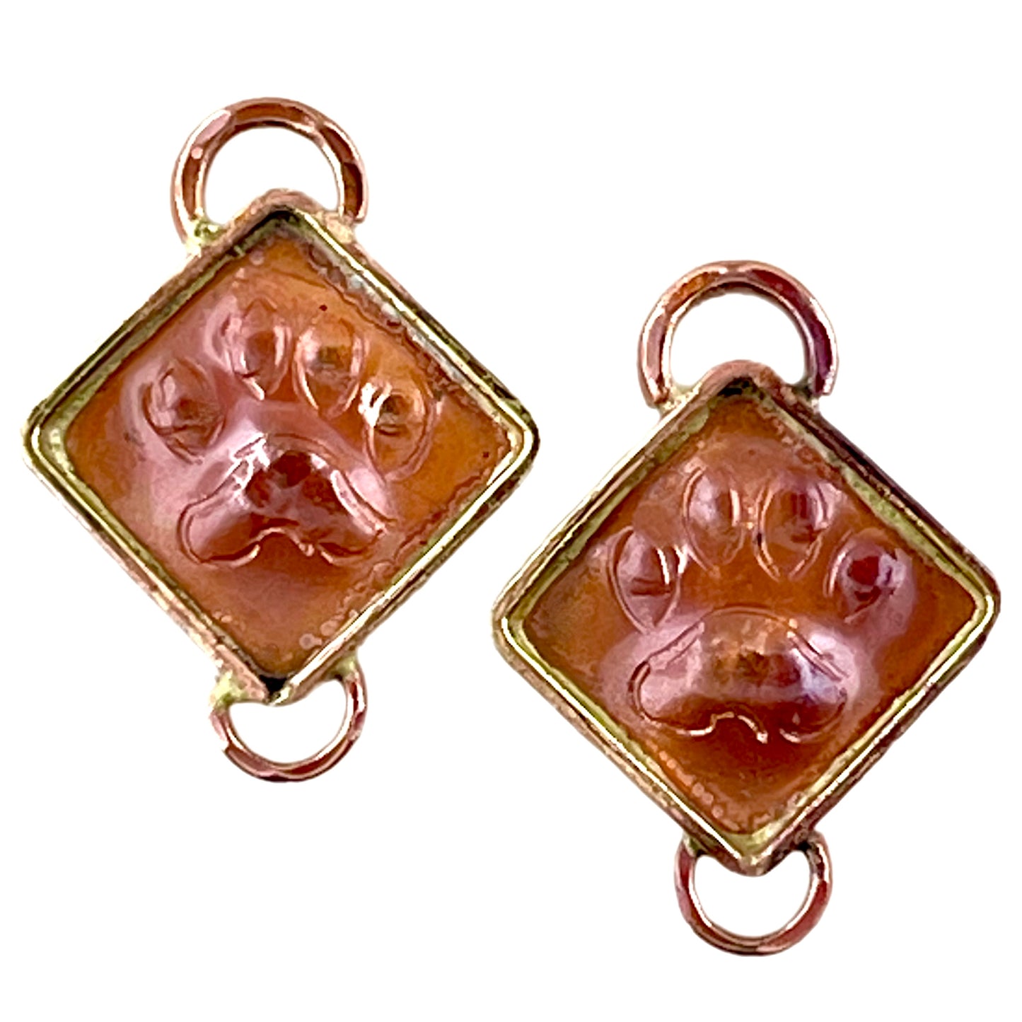 Copper paw print components with brass accents and red flame patina, handcrafted by Patricia Healey for earrings or pet-themed links.