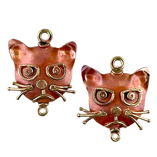 Close-up of handcrafted angry cat copper earring components with brass accents and flame-fired red patina