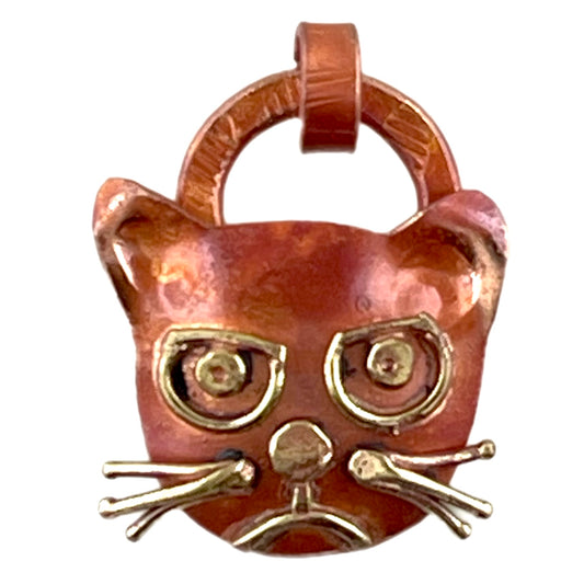 Small copper angry cat pendant with brass accents and red flame patina, handcrafted by Patricia Healey for playful pet-themed jewelry.