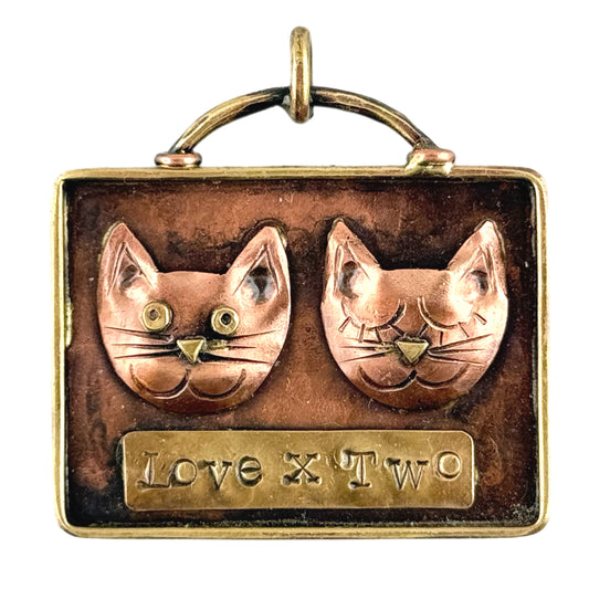Copper pendant featuring two cats with brass accents and antiqued flame patina, handcrafted by Patricia Healey.