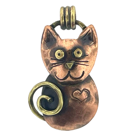 Antiqued copper cat pendant with hand-stamped heart, brass accents, and red patina, handcrafted by Patricia Healey using repoussé technique.