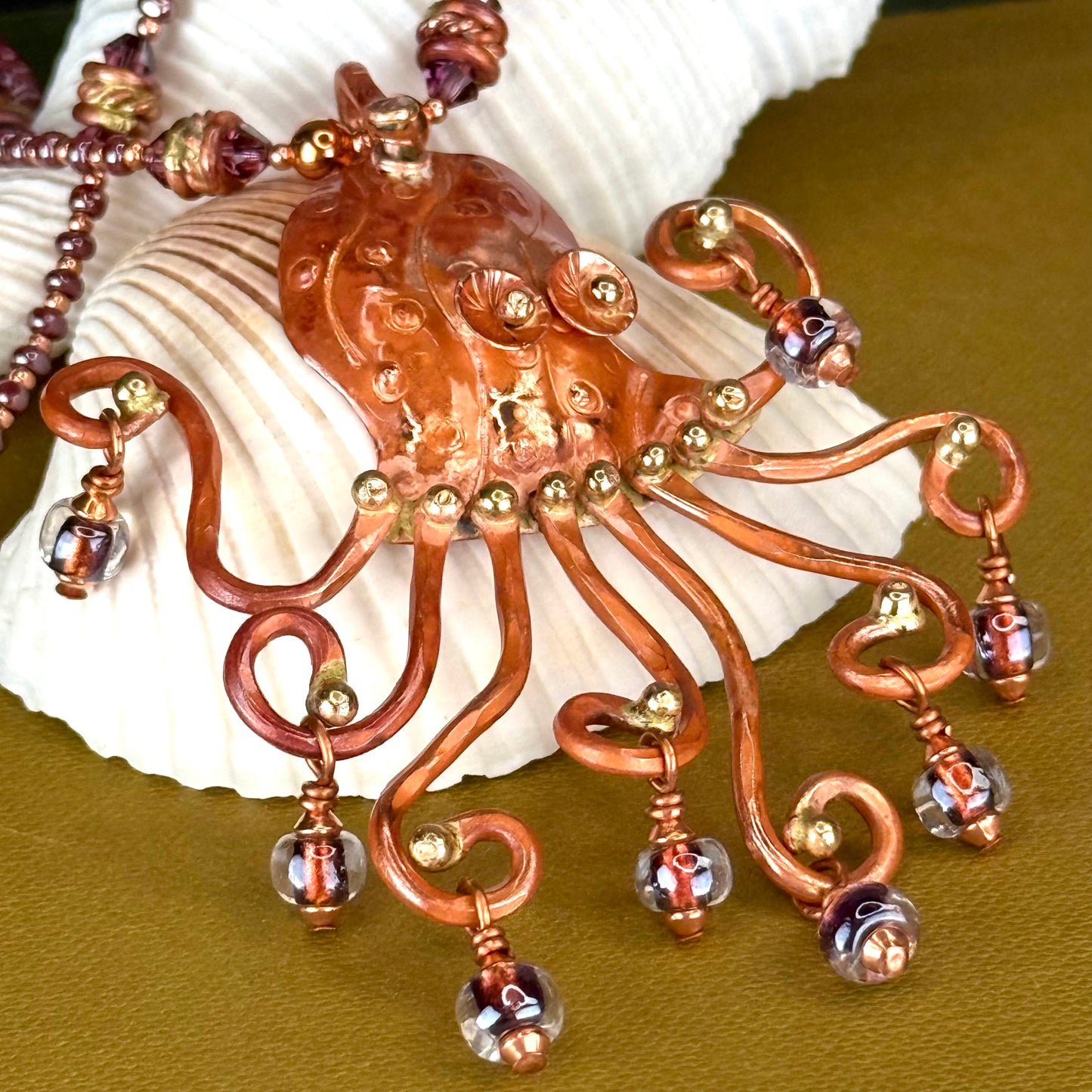 Handmade flame-finished copper octopus necklace with purple Japanese dichroic glass beads, brass, and Swarovski crystals on a beaded strand.