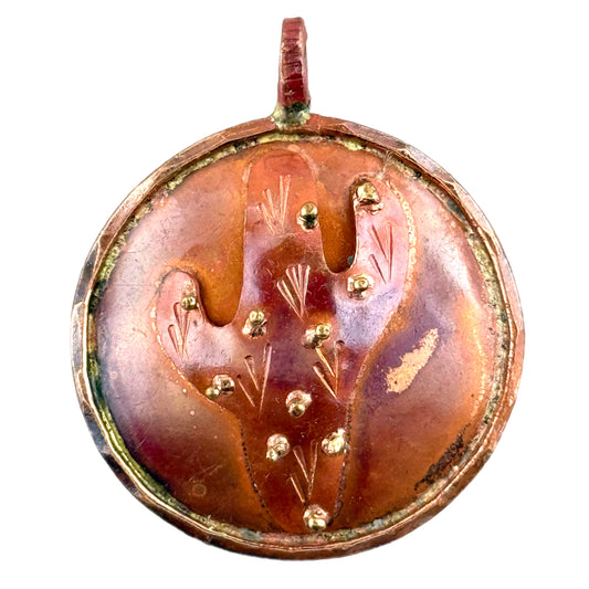 Close-up of rustic copper cactus pendant with brass accents, torch-heated patina