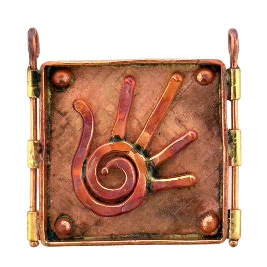 Handmade copper and brass pendant with raised spiral hand design, square shape, flame-heated finish, and textured background.