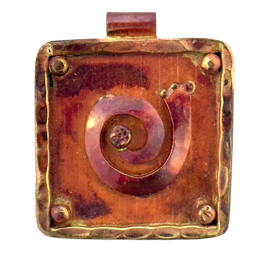 Handmade copper and brass pendant with raised spiral design, square shape, and flame-finished surface.