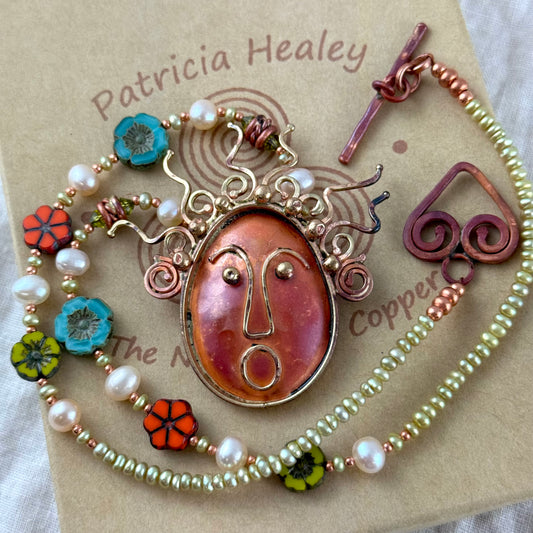 Whimsical copper face pendant necklace with brass accents, pearls, and Czech glass flower beads in playful colors