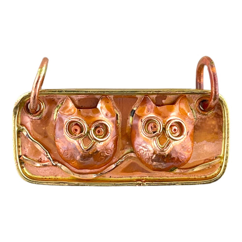 Copper pendant of two owls on a branch with brass detail, flame patina, and stamped wings
