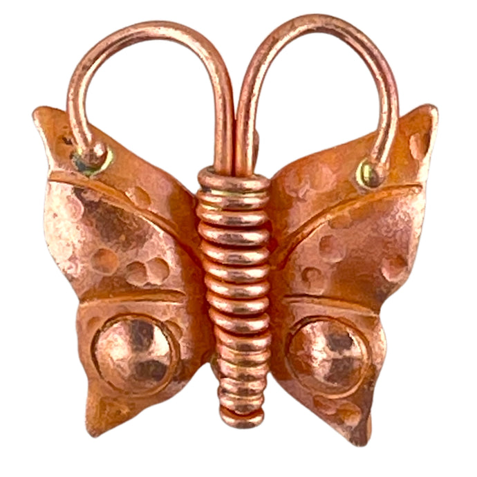 Handcrafted copper butterfly pendant with coiled body and textured wings in red and orange tones


