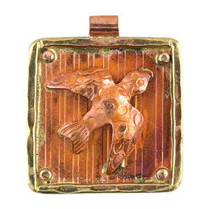 Handcrafted flying dove pendant in copper with brass frame, flame-patina in reds and oranges