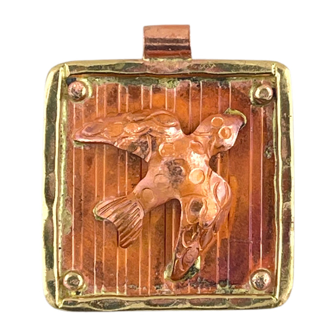 Handcrafted flying dove pendant in copper with brass frame, flame-patina in reds and oranges