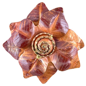 Handmade copper flower pendant with three repoussé layers, hand-stamped texture, red-orange patina, and brass spiral center by Patricia Healey
